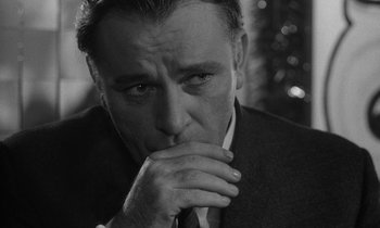 Movie still from “The Spy Who Came in from the Cold” (1965), directed by Martin Ritt – Black and white photograph of a man in a suit and tie looking pensive; Close Up shot, Over the shoulder angle