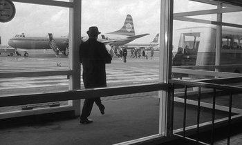 Movie still from “The Spy Who Came in from the Cold” (1965), directed by Martin Ritt – A black and white photo of a man walking through an airport; Wide shot, Over the shoulder angle
