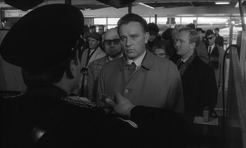 Movie still from “The Spy Who Came in from the Cold” (1965), directed by Martin Ritt – A black and white photo of a man in a crowd of people; Medium shot, Over the shoulder angle