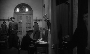 Movie still from “The Spy Who Came in from the Cold” (1965), directed by Martin Ritt – A man sitting at a table in a room; Wide shot, High angle