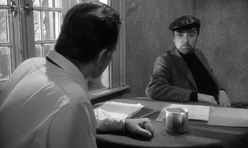 Movie still from “The Spy Who Came in from the Cold” (1965), directed by Martin Ritt – A man sitting at a table in front of another man; Medium shot, Over the shoulder angle