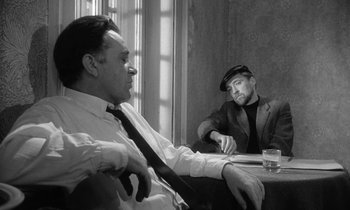 Movie still from “The Spy Who Came in from the Cold” (1965), directed by Martin Ritt – Two men sitting at a table in front of each other; Medium shot, Over the shoulder angle