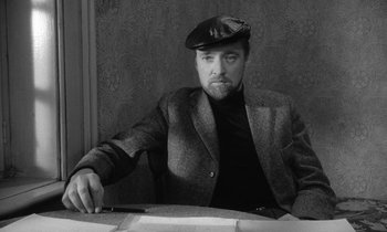 Movie still from “The Spy Who Came in from the Cold” (1965), directed by Martin Ritt – A black and white photo of a man sitting at a table; Medium shot, High angle