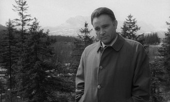 Movie still from “The Spy Who Came in from the Cold” (1965), directed by Martin Ritt – A black and white photo of a man standing in a wooded area; Medium shot, Low angle
