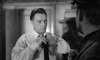 Movie still from “The Spy Who Came in from the Cold” (1965), directed by Martin Ritt – A black and white photo of a man tying his tie; Close Up shot, Over the shoulder angle