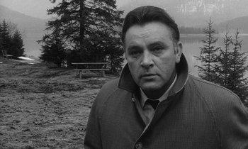 Movie still from “The Spy Who Came in from the Cold” (1965), directed by Martin Ritt – Black and white photograph of a man in front of a body of water; Close Up shot, Low angle