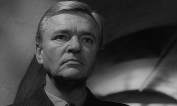 Movie still from “The Spy Who Came in from the Cold” (1965), directed by Martin Ritt – Black and white photograph of a man in a suit; Close Up shot, Low angle