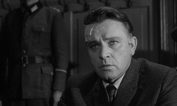 Movie still from “The Spy Who Came in from the Cold” (1965), directed by Martin Ritt – A man in a suit and tie looking at the camera; Close Up shot, Low angle