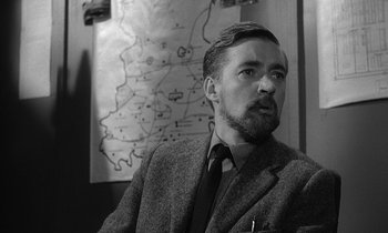 Movie still from “The Spy Who Came in from the Cold” (1965), directed by Martin Ritt – Black and white photograph of a man in front of a map; Close Up shot, Over the shoulder angle