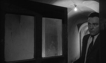 Movie still from “The Spy Who Came in from the Cold” (1965), directed by Martin Ritt – A person is walking down a hallway in a building; Wide shot, Low angle