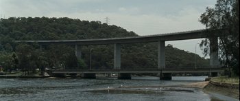 Movie still from “The Square” (2008), directed by Nash Edgerton – A bridge over a body of water near a wooded area; Extreme Wide shot, High angle