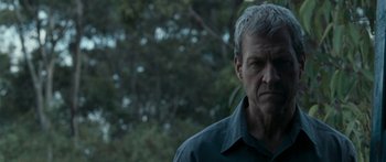 Movie still from “The Square” (2008), directed by Nash Edgerton – An older man standing in front of a tree; Close Up shot, Over the shoulder angle