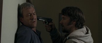 Movie still from “The Square” (2008), directed by Nash Edgerton – A man holding a gun pointed at another man's face; Close Up shot, Over the shoulder angle