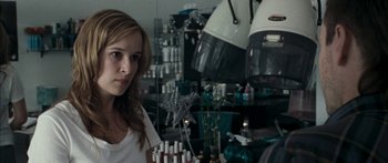 Movie still from “The Square” (2008), directed by Nash Edgerton – A woman standing in front of a bunch of candles in a room; Close Up shot, Over the shoulder angle