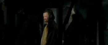 Movie still from “The Square” (2008), directed by Nash Edgerton – A man with a long beard standing in a dark room; Medium shot, Low angle