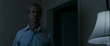 Movie still from “The Square” (2008), directed by Nash Edgerton – A man standing in front of a door in a dark room; Close Up shot, Low angle