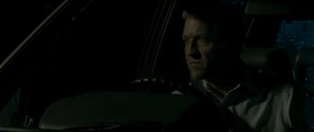 Movie still from “The Square” (2008), directed by Nash Edgerton – A person with a cello in a dark room; Close Up shot, Over the shoulder angle