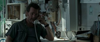 Movie still from “The Square” (2008), directed by Nash Edgerton – A man sitting at a desk talking on a phone; Close Up shot, Overhead angle