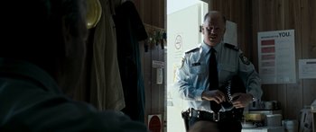 Movie still from “The Square” (2008), directed by Nash Edgerton – A man in a uniform standing in front of a door; Medium shot, Over the shoulder angle