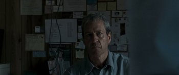 Movie still from “The Square” (2008), directed by Nash Edgerton – A man in a blue shirt in front of a bunch of papers; Close Up shot, Over the shoulder angle