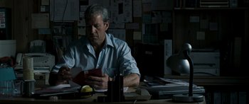 Movie still from “The Square” (2008), directed by Nash Edgerton – A man sitting at a desk looking at a book; Medium shot, Low angle