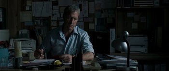 Movie still from “The Square” (2008), directed by Nash Edgerton – A man sitting at a desk in front of papers; Medium shot, Low angle
