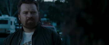 Movie still from “The Square” (2008), directed by Nash Edgerton – A man with a beard is standing in the dark; Close Up shot, Over the shoulder angle