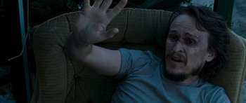 Movie still from “The Square” (2008), directed by Nash Edgerton – A man sitting on a couch with his hand in the air; Close Up shot, High angle