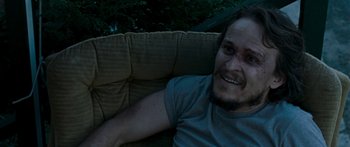 Movie still from “The Square” (2008), directed by Nash Edgerton – A man with a bandage on his face is laying on a couch; Close Up shot, High angle