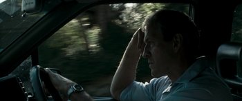 Movie still from “The Square” (2008), directed by Nash Edgerton – A man sitting in the driver's seat of a car while talking on the phone; Close Up shot, Over the shoulder angle