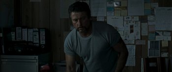 Movie still from “The Square” (2008), directed by Nash Edgerton – A man standing in a room next to a wall; Medium shot, Over the shoulder angle
