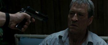 Movie still from “The Square” (2008), directed by Nash Edgerton – An older man holding a gun pointed at a younger man; Close Up shot, Over the shoulder angle