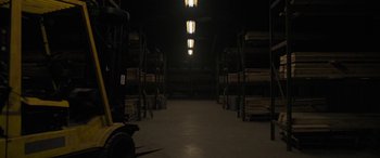 Movie still from “The Standoff at Sparrow Creek” (2018), directed by Henry Dunham – A warehouse filled with lots of shelves of lumber; Extreme Wide shot, Low angle