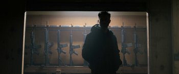 A man standing in front of a wall of guns