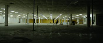Two people in a large empty room with yellow walls