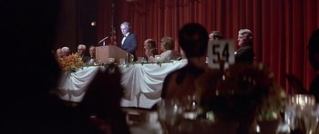 Movie still from “The Star Chamber” (1983), directed by Peter Hyams – A man standing at a podium in front of a group of people; Medium shot, Over the shoulder angle