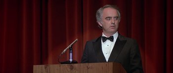 Movie still from “The Star Chamber” (1983), directed by Peter Hyams – A man standing at a podium in front of a microphone; Close Up shot, Low angle