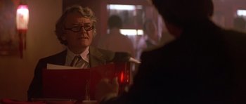 Movie still from “The Star Chamber” (1983), directed by Peter Hyams – A man sitting at a table in front of a glass of wine; Close Up shot, Over the shoulder angle