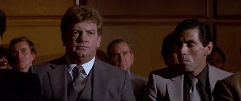 Movie still from “The Star Chamber” (1983), directed by Peter Hyams – A man wearing a suit and tie in a courtroom; Close Up shot, Low angle
