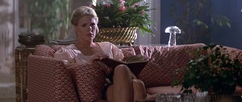 Movie still from “The Star Chamber” (1983), directed by Peter Hyams – A woman sitting on top of a couch reading a book; Medium shot, Low angle