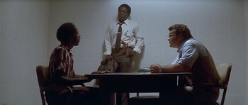 Movie still from “The Star Chamber” (1983), directed by Peter Hyams – Three people sitting at a table in front of a man; Medium shot, Over the shoulder angle
