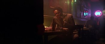 Movie still from “The Star Chamber” (1983), directed by Peter Hyams – A man sitting at a table with a bottle of wine; Medium shot, Low angle