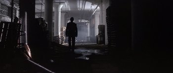 Movie still from “The Star Chamber” (1983), directed by Peter Hyams – A man walking in a dark room with a lot of trash; Wide shot, Over the shoulder angle