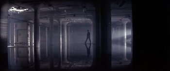 Movie still from “The Star Chamber” (1983), directed by Peter Hyams – A man is walking in a dark building; Extreme Wide shot, High angle