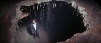 Movie still from “The Star Chamber” (1983), directed by Peter Hyams – A man standing in front of an entrance to a cave; Wide shot, High angle