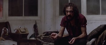 Movie still from “The Star Chamber” (1983), directed by Peter Hyams – A man sitting on the ground in a room; Medium shot, Low angle