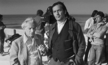 Movie still from “The State of Things” (1982), directed by Wim Wenders – A man standing next to another man on the beach; Medium shot, Over the shoulder angle