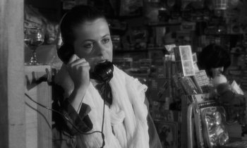 Movie still from “The State of Things” (1982), directed by Wim Wenders – A young woman talking on a phone while wearing a scarf; Close Up shot, High angle