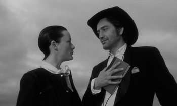 Movie still from “The State of Things” (1982), directed by Wim Wenders – A man and a woman standing next to each other; Medium shot, Low angle