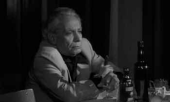 Movie still from “The State of Things” (1982), directed by Wim Wenders – An older man sitting at a table with a glass of wine; Close Up shot, Low angle